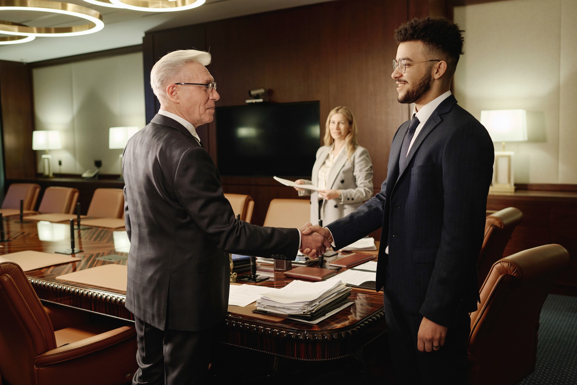 Caucasian and Middle Eastern Men Shaking Hands Standing in Office Boardroom